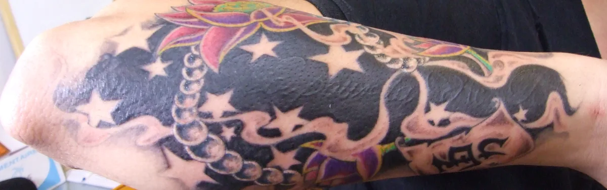 Lettrage recouvert par une manchette noire avec étoiles, perles et lotus, cover up de Tof