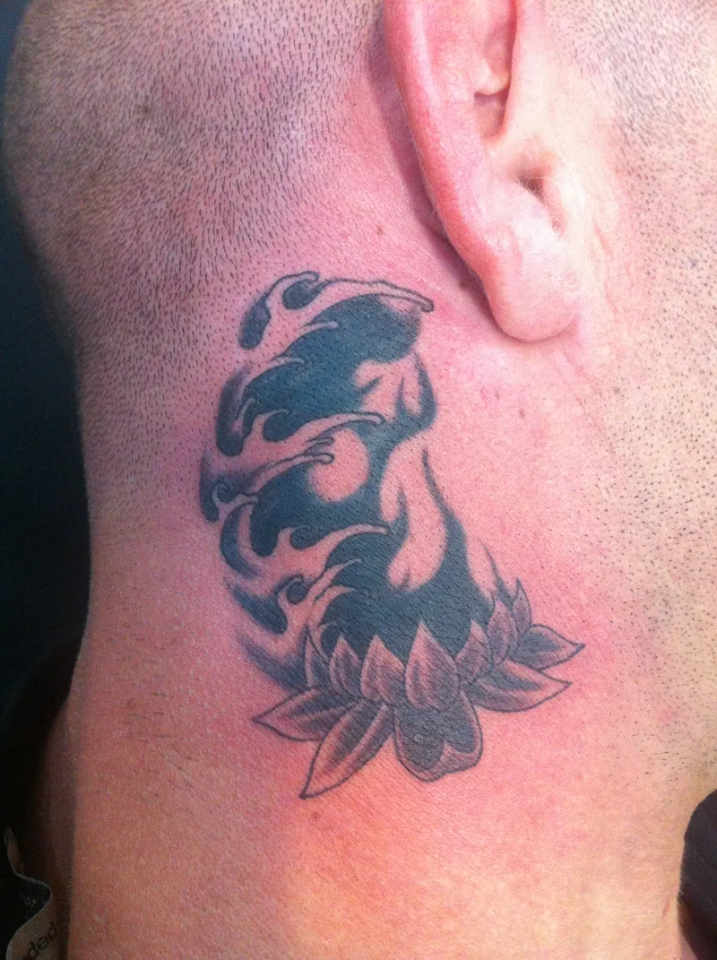 Flammes noires et lotus recouvrant un motif rouge derrière l'oreille, cover up de Tof