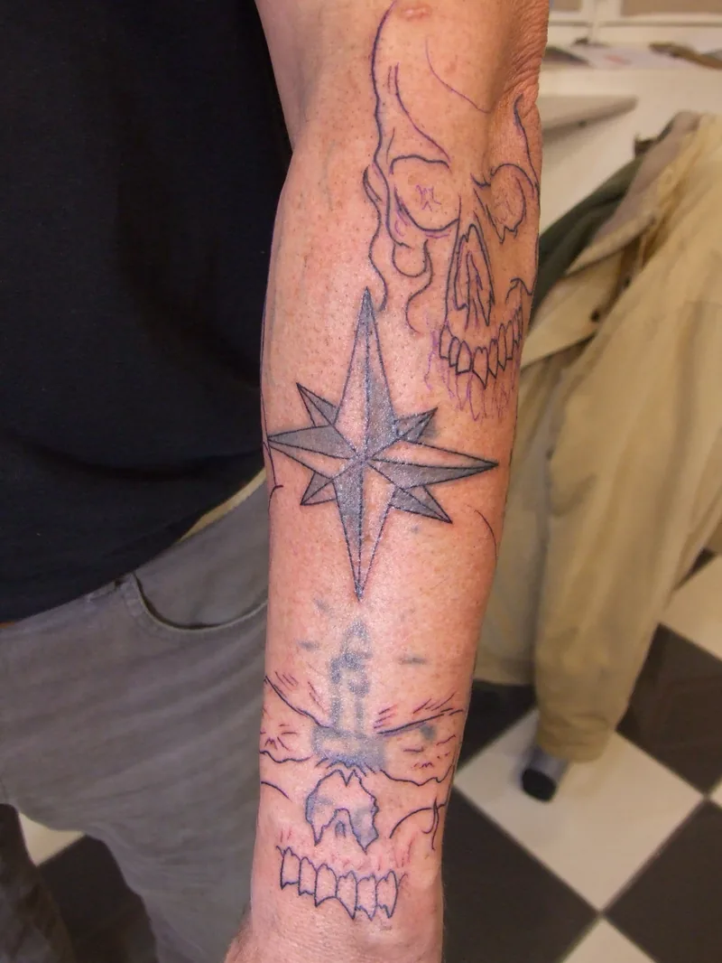 Avant-bras avec une étoile et un ancien tatouage, et le tracé d'un nouveau dessin de crânes