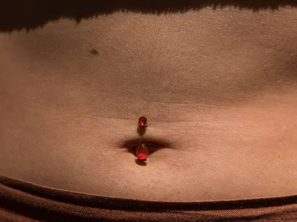 Piercing du nombril avec un bijou grenat posé chez Tattoo on Move